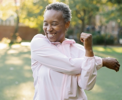woman smiling and stretching arm muscles